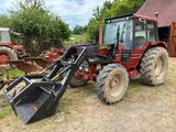 un tracteur rouge garé sur la terre battue