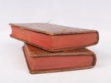 three old books stacked on top of each other on a white surface