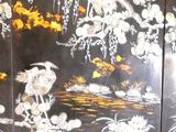 a black and gold screen with flowers and birds on it