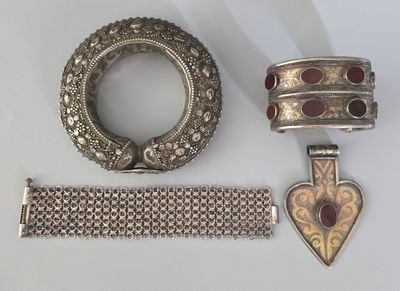 bracelet en argent, bague et bracelet ornés de pierres rouges sur un fond blanc