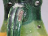 a green and yellow vase with a handle on a table