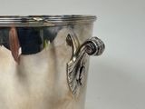 a silver vase with a handle on a white table