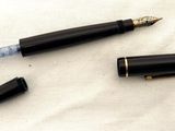 un stylo noir et un stylo à plume noir posés sur un tissu blanc