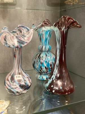 three glass vases sitting on a glass shelf