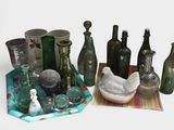 many glass bottles and vases sitting on a table