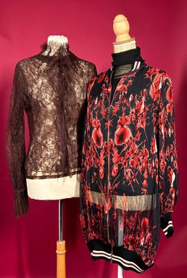 two women ' s jackets on a mannequin stand against a red background