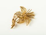 a close up of a gold brooch with leaves on it