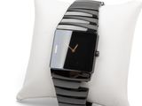 a black watch on a white pillow on a white pillow