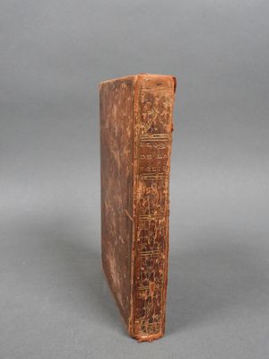 un vieux livre posé sur une table à côté d'un fond gris