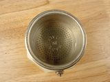 a metal strainer that is on a wooden table