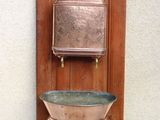 un évier en cuivre fixé au mur, devant une porte en bois