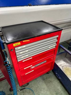 une armoire à outils rouge avec un dessus noir, dans un garage