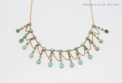 a gold necklace with turquoise stones on a white background
