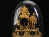 une horloge dorée sous un dôme en verre sur fond noir
