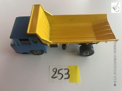 un camion-benne jouet jaune et bleu posé sur une table blanche