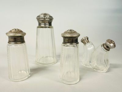 three glass salt and pepper shakers with silver tops on a white surface