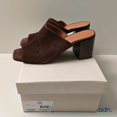 a pair of brown sued mules on top of a white box