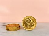 two gold coins sitting next to each other on a marble surface