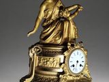 a gold clock with a statue on top of it