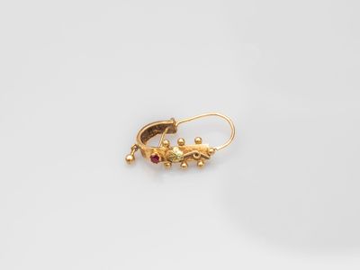 a pair of gold earrings on a white surface