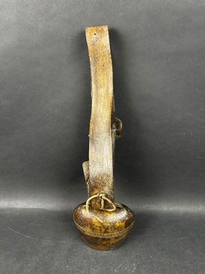 une vieille cloche en laiton munie d'une poignée en bois, sur fond noir