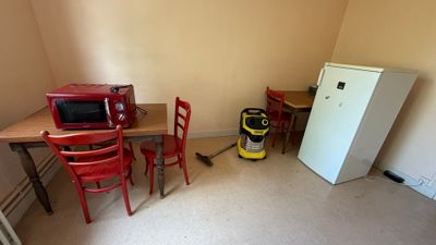 une pièce équipée d'une table, de chaises, d'un réfrigérateur et d'un micro-ondes