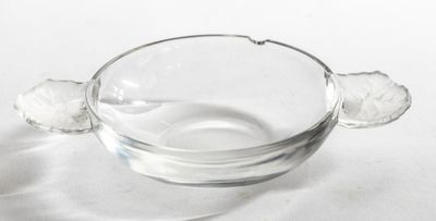 un saladier en verre muni d'une poignée, posé sur une surface blanche