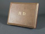 an old brown book with gold lettering sitting on top of a table