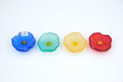 four plastic flowers are lined up in a row on a white surface