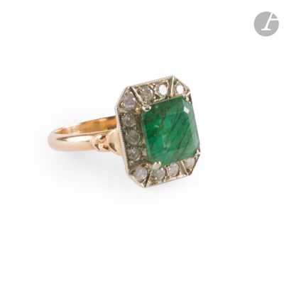 a close up of a ring with a green stone surrounded by diamonds