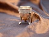 a silver goblet sitting on top of a brown cloth