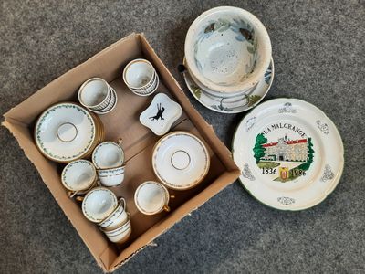 une boîte contenant des tasses à thé et leurs soucoupes, posée par terre