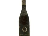 an old bottle of wine sitting on top of a white surface