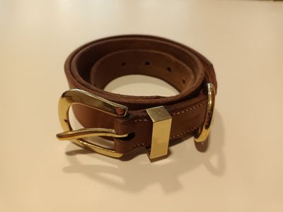une ceinture marron avec une boucle dorée posée sur une table