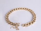 a close up of a gold bracelet on a white surface