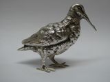 un oiseau argenté posé sur une surface blanche