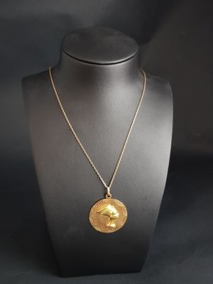 a gold necklace with a bird on it on a mannequin