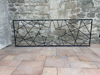 une clôture en fer noir posée sur un sol en briques, près d'un mur de pierre