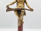 statue d'un ange lisant un livre, posée sur un socle rouge