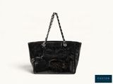 black leather handbag with chain handles on a white background