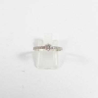 une photo d'une bague en diamant posée sur un bloc transparent