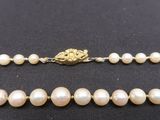 a close up of a necklace with pearls on a black surface