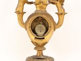 a gold clock with angels around it on a stand