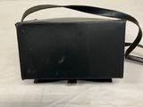 a black purse with a strap on it sitting on a white surface