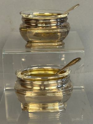 two bowls and spoons sitting on a clear shelf