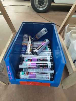un bac bleu rempli de pots de peinture et de colle