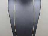 a gold chain necklace on a mannequin display