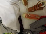 a suitcase full of clothes and shoes sitting on a bed