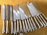 six couteaux en métal argenté sont alignés sur une table