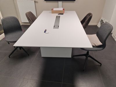 une grande table blanche entourée de chaises dans une pièce